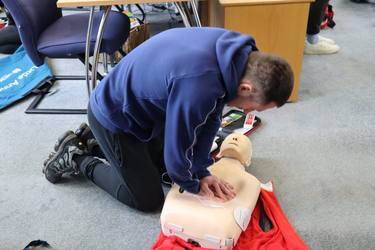 A young person practicing CPR on a CPR training manikin. 